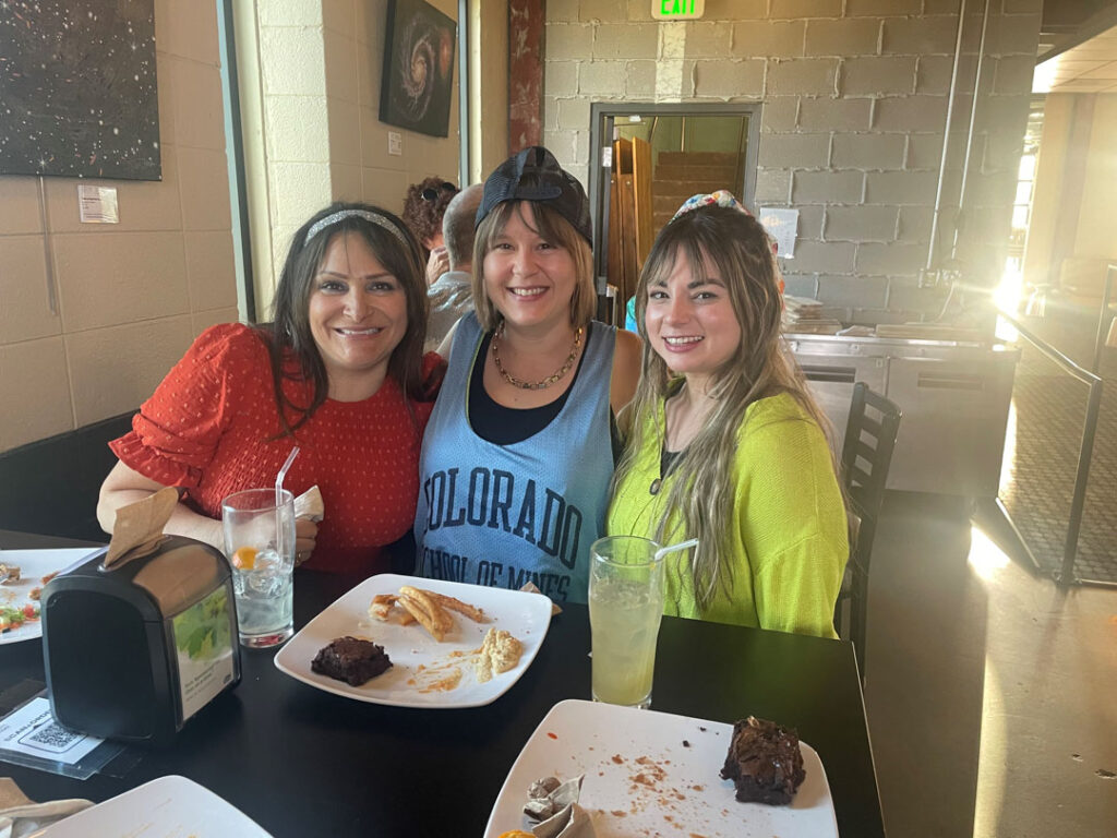 Three ARKA employees smiling around a table at a restaurant.