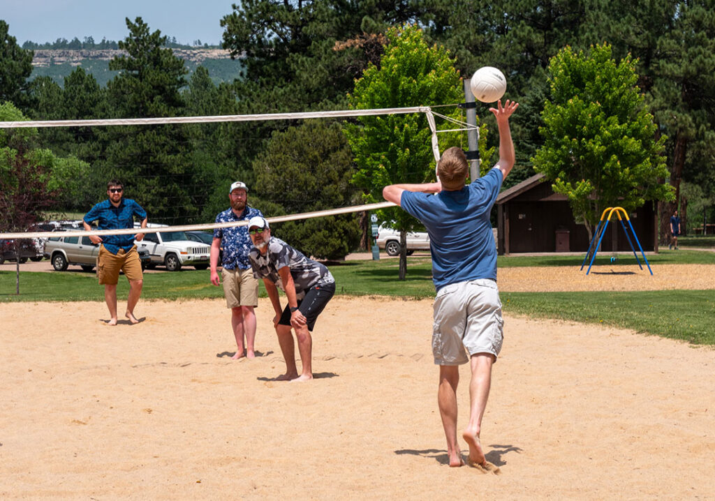 four men playing volleyball on sand